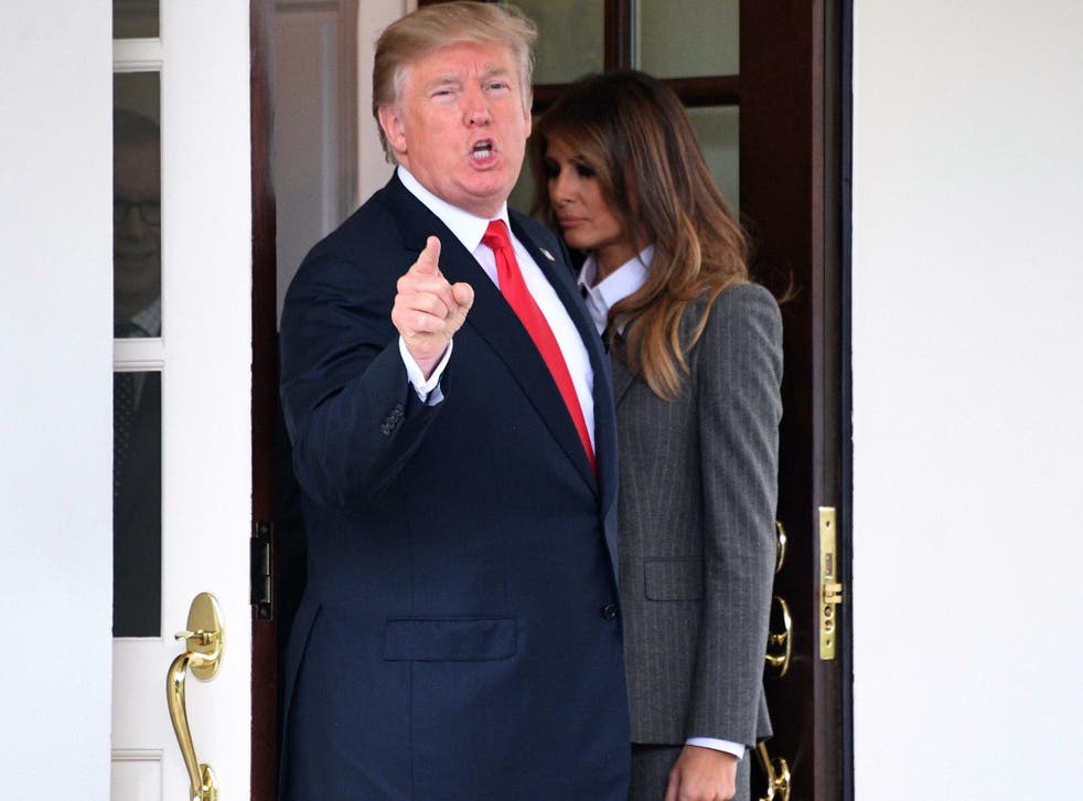 US President Donald Trump answers a question from the press as First Lady Melania Trump walks back into the White House on 11 October 2017.
