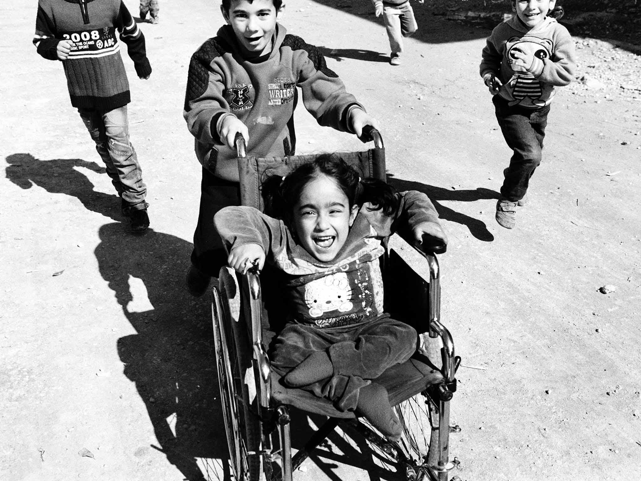 Aya laughs as her brother, Mohamad, pushes her around in her wheelchair in Tripoli