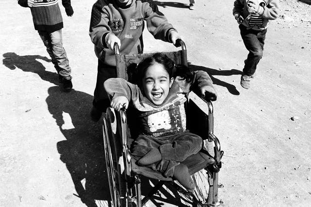 Aya laughs as her brother, Mohamad, pushes her around in her wheelchair in Tripoli