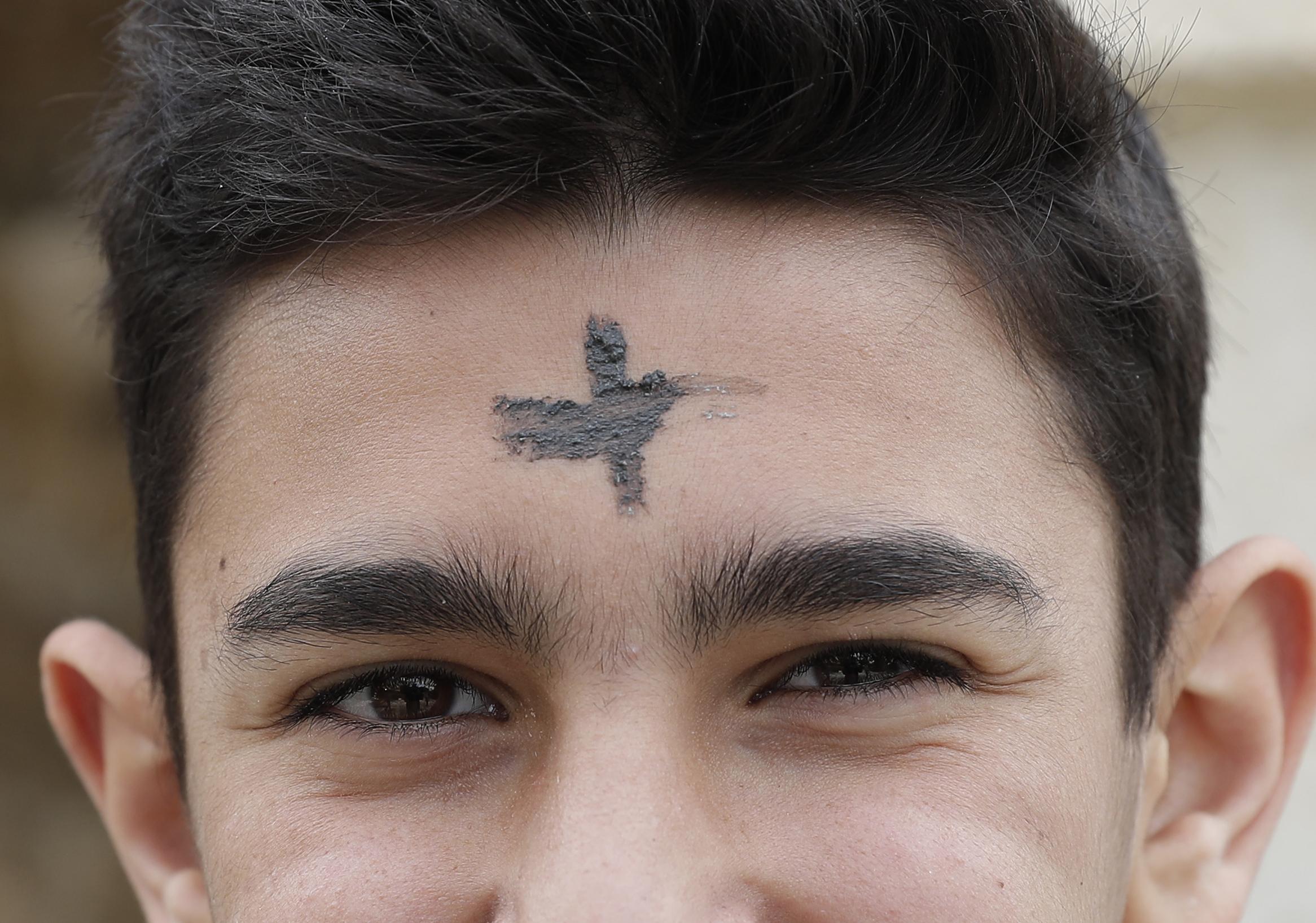 A Lebanese Christian youth, bearing an ash cross on his forehead, looks on after leaving church in the coastal city of Byblos north of Beirut, on February 27, 2017