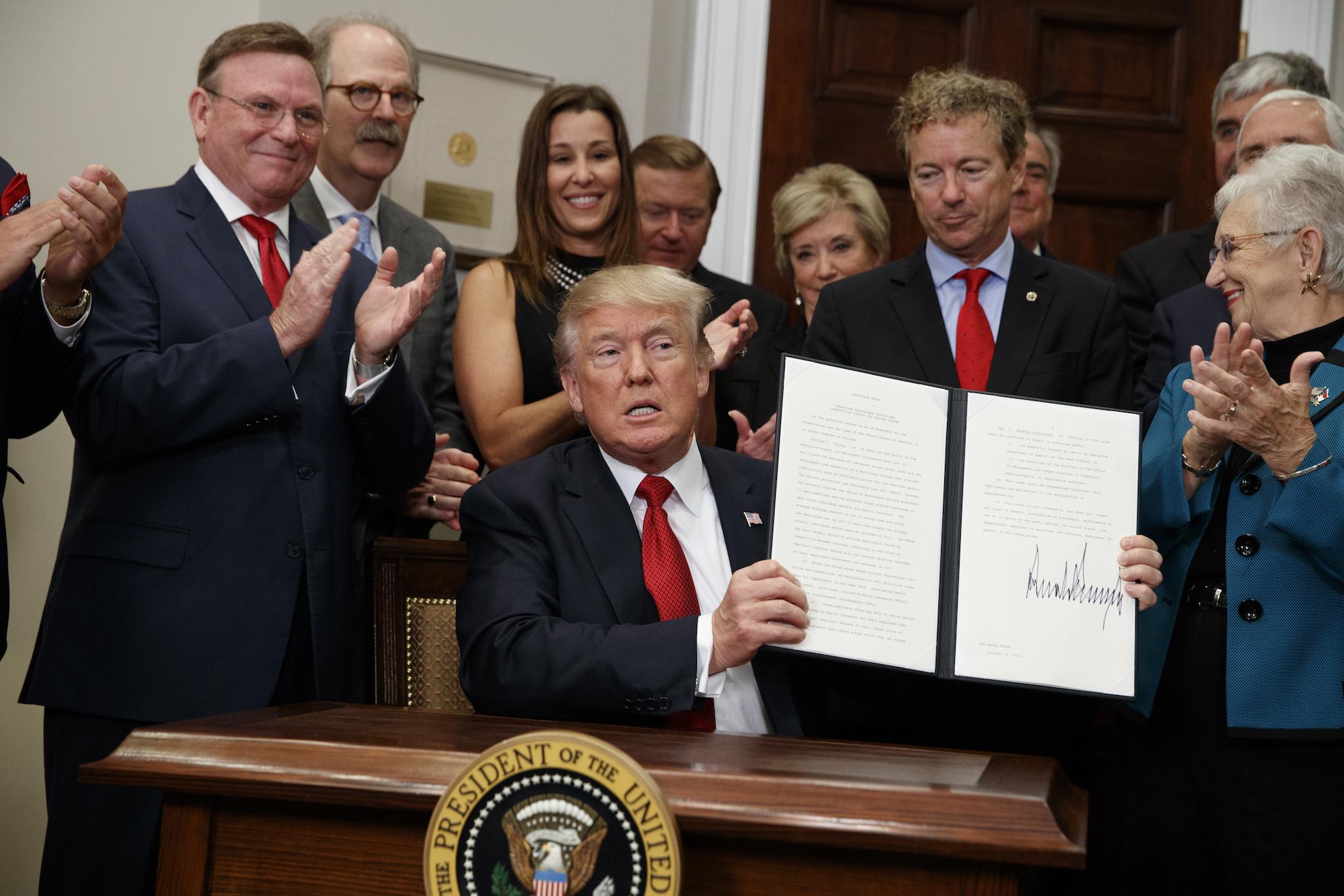 President Donald Trump shows an executive order on healthcare that he signed in the Roosevelt Room of the White House