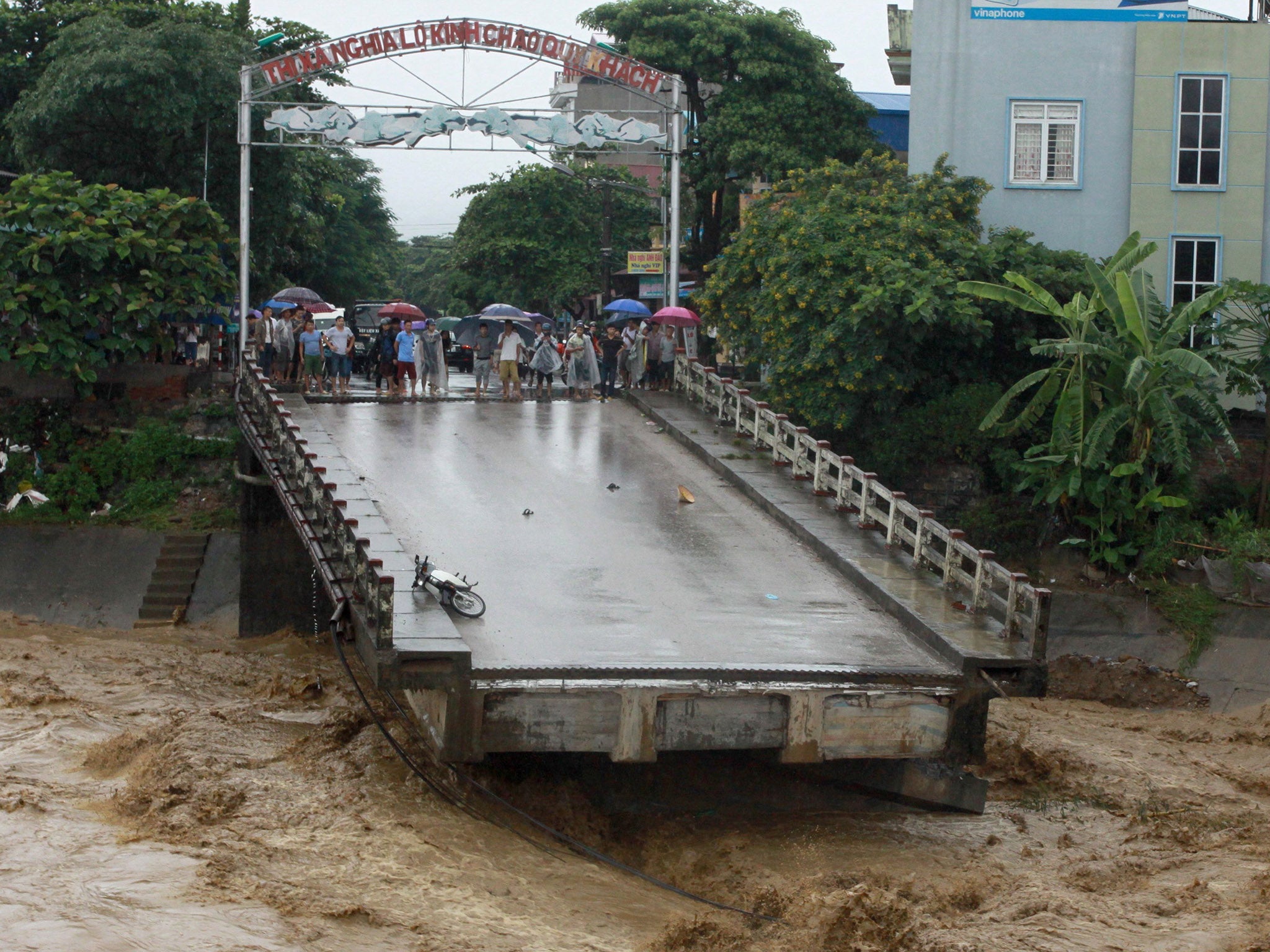 Residents standing at the end of a destroyed bridge in the northern province of Yen Bai