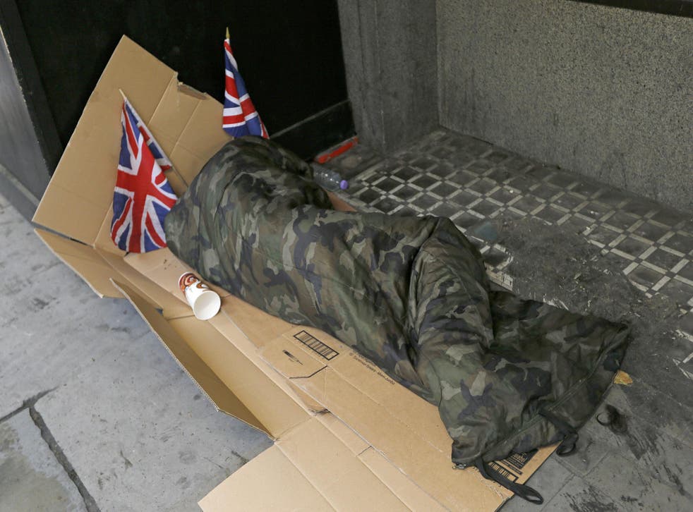 A homeless person lays on cardboard decorated with Union Flags in central London