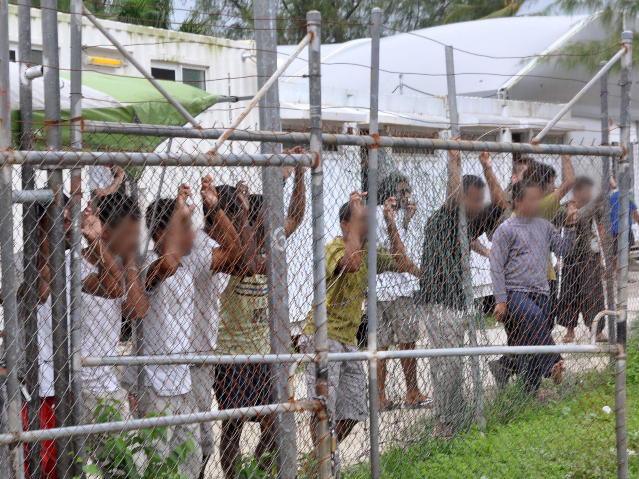 Asylum-seekers look through a fence at the Manus Island detention centre in Papua New Guinea
