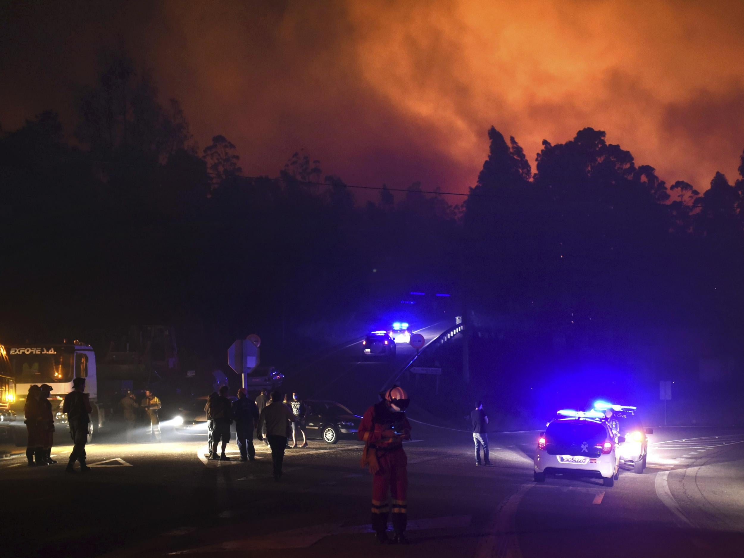 Police cars block the area as emergency vehicles responded to a fire in As Neves, Pontevedra, as wildfires grip the Iberian Peninsula