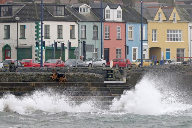 A woman walks her dogs beside the stormy sea in the coastal village of Donaghadee on the Irish Sea coast, east of Belfast