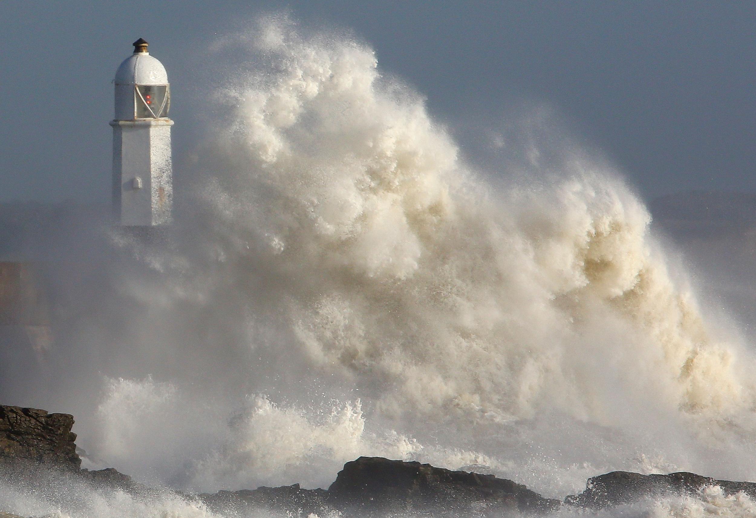 Huge waves strike the harbour wall and lighthouse at Porthcawl, South Wales, on October 16, 2017 as Storm Ophelia hits the UK and Ireland.