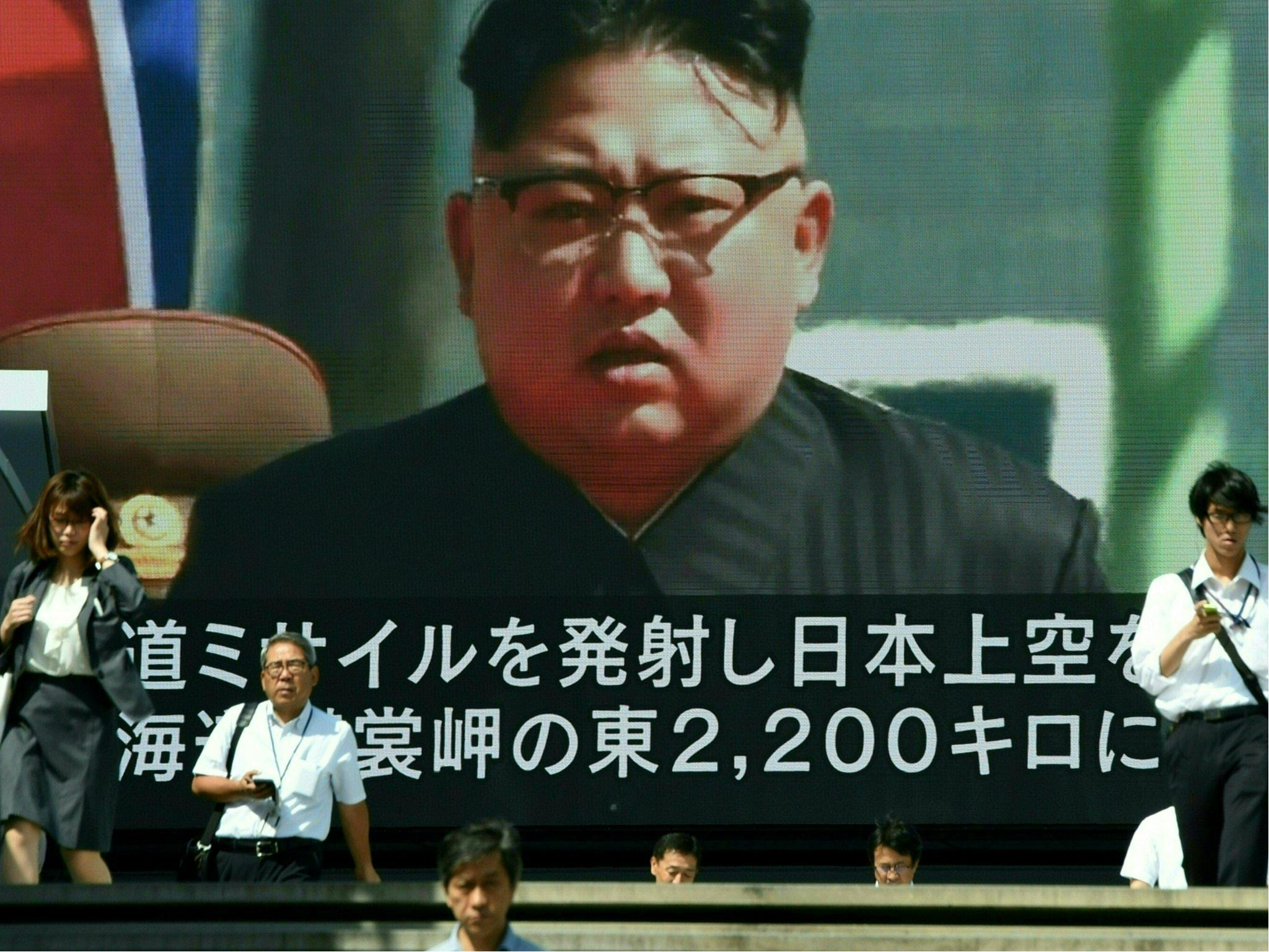 Pedestrians walk in front of a large video screen in Tokyo broadcasting a news report showing North Korean leader Kim Jong-Un (File photo)