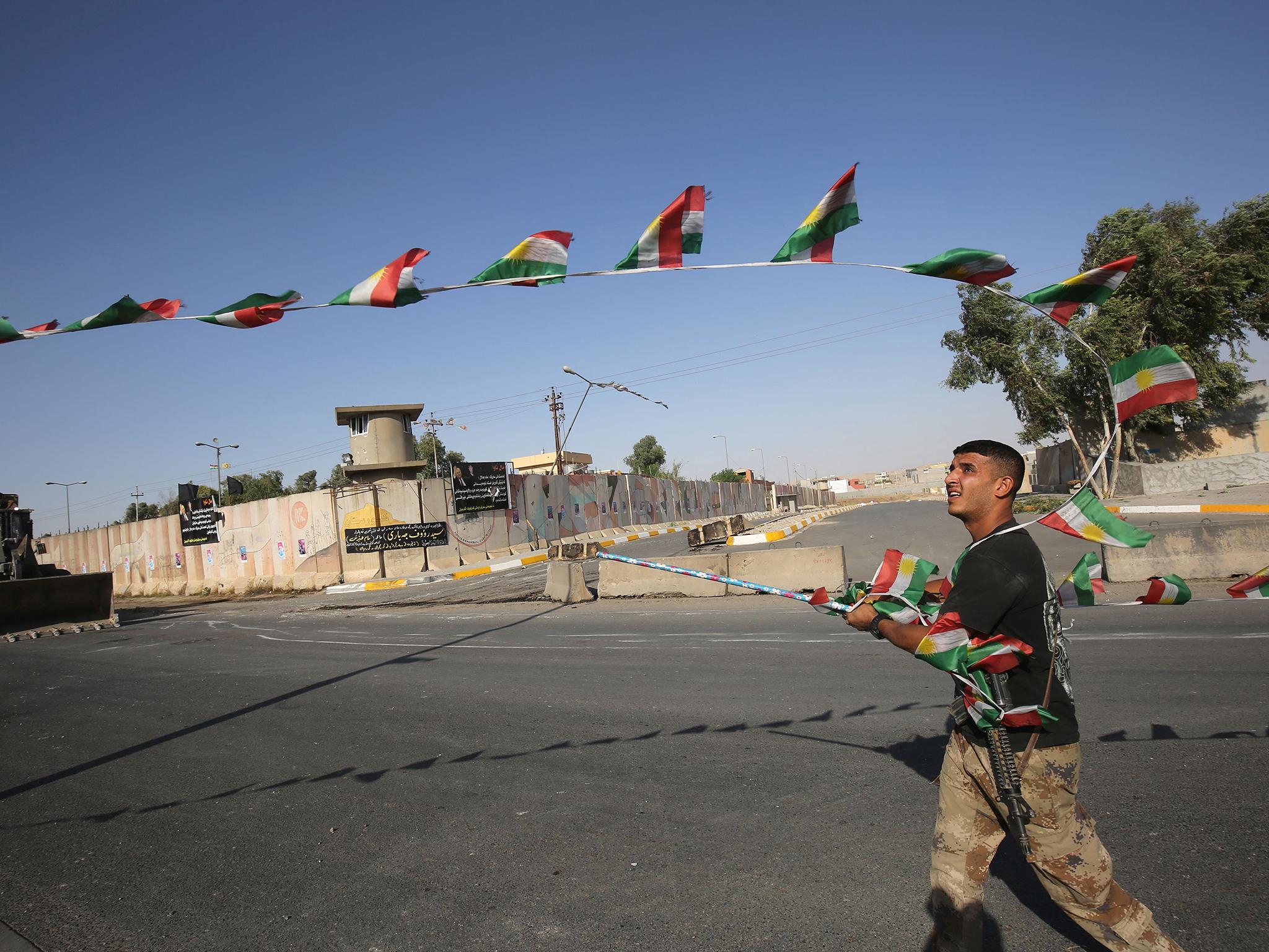 An Iraqi forces member takes down Kurdish flags as they advance towards the centre of Kirkuk during an operation against Kurdish fighters