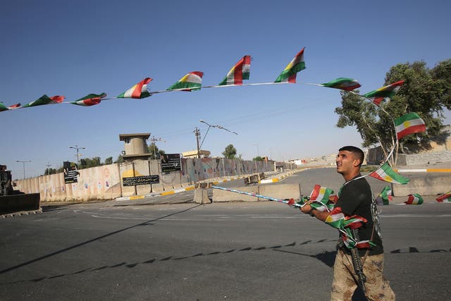 An Iraqi forces member takes down Kurdish flags as they advance towards the centre of Kirkuk during an operation against Kurdish fighters