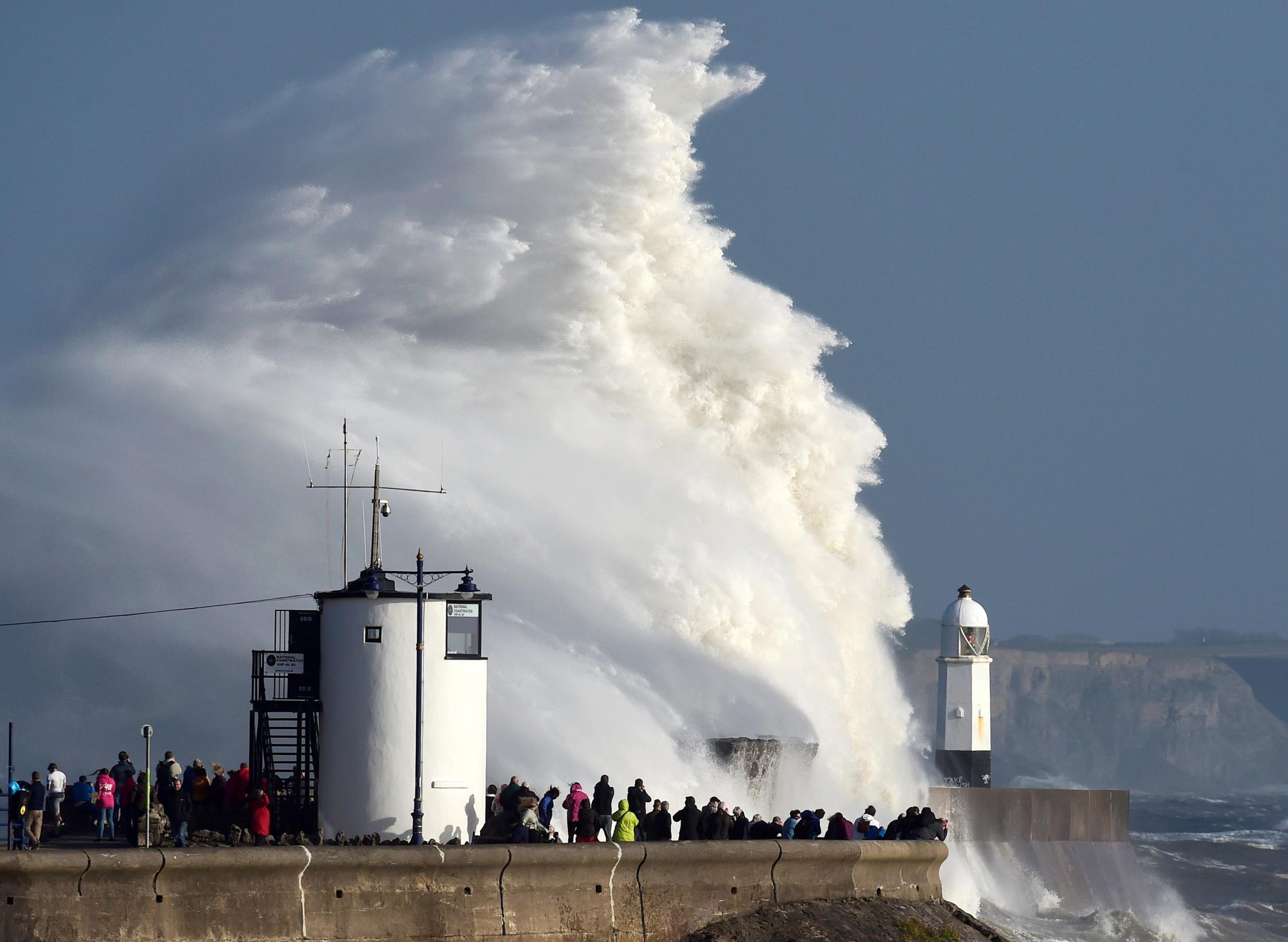 Waves crash over a lighthouse as storm Ophelia passes Porthcawl, Wales