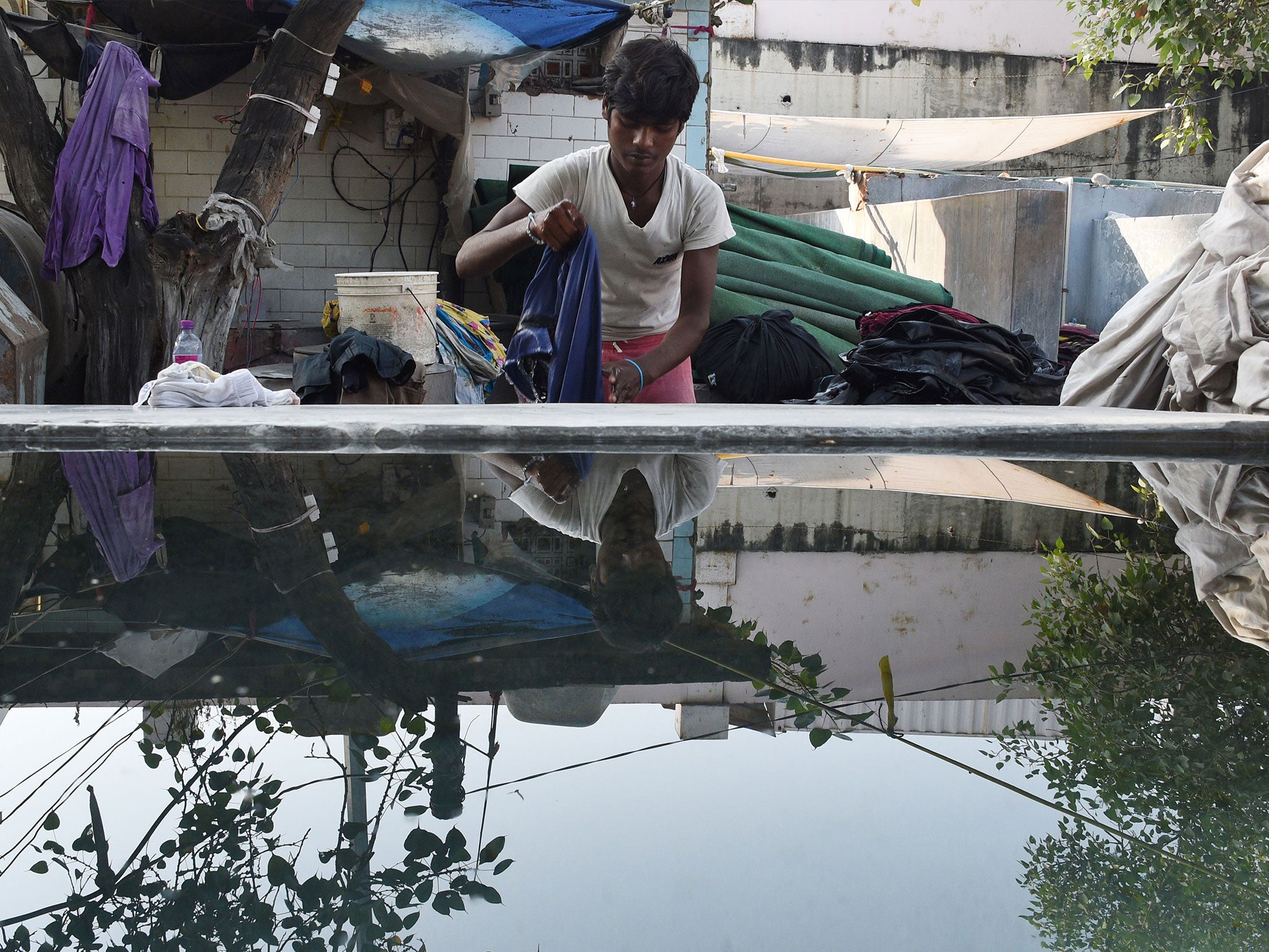 A worker washes clothes in the early morning at an open-air laundry facility in New Delhi