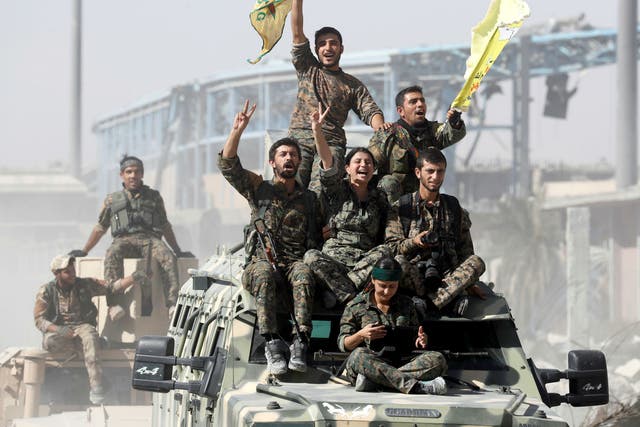 Syrian Democratic Forces (SDF) fighters ride atop military vehicles as they celebrate victory in Raqqa