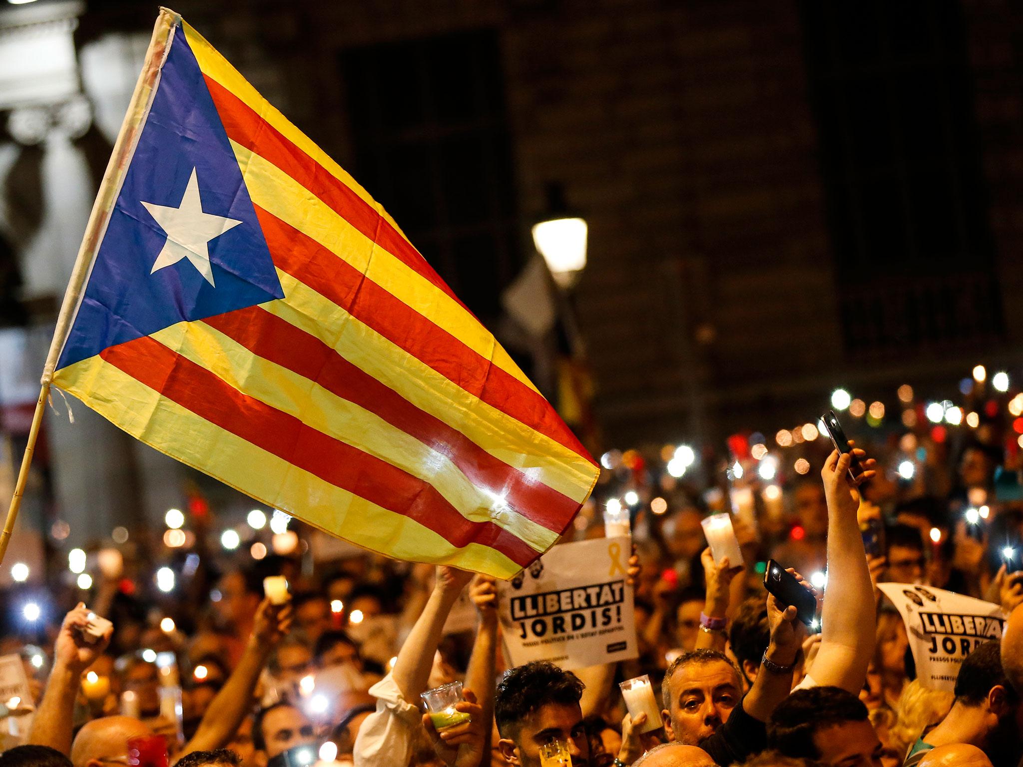 People hold candles and a Catalan pro-independence 'Estelada' flag during a demonstration in Barcelona against the arrest of two Catalan separatist leaders