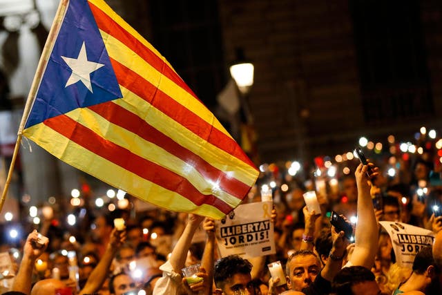 People hold candles and a Catalan pro-independence 'Estelada' flag during a demonstration in Barcelona against the arrest of two Catalan separatist leaders