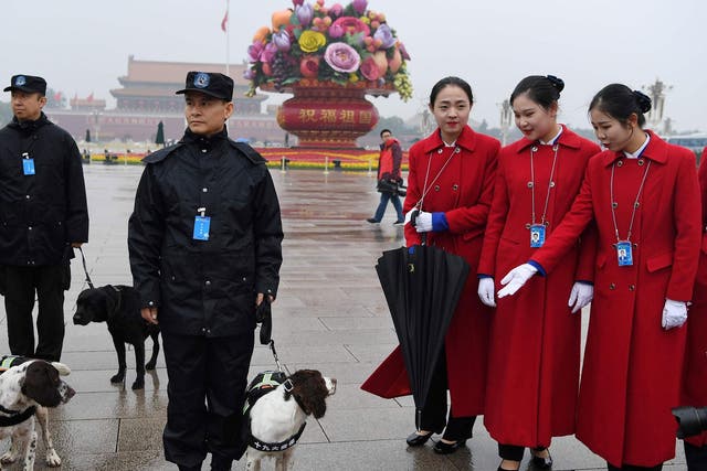Attendants look at sniffer dogs while posing for photos in Tiananmen Square during the opening ceremony of the 19th Communist Party Congress in Beijing