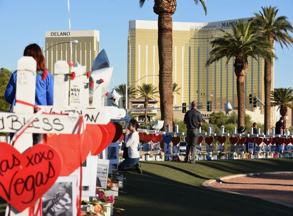 A woman prays beside 58 white crosses for the victims of a mass shooting, on Las Vegas Strip just south of the Mandalay Bay hotel