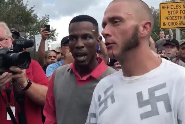 A man wearing a shirt emblazoned with swastikas gets punched and spat on.