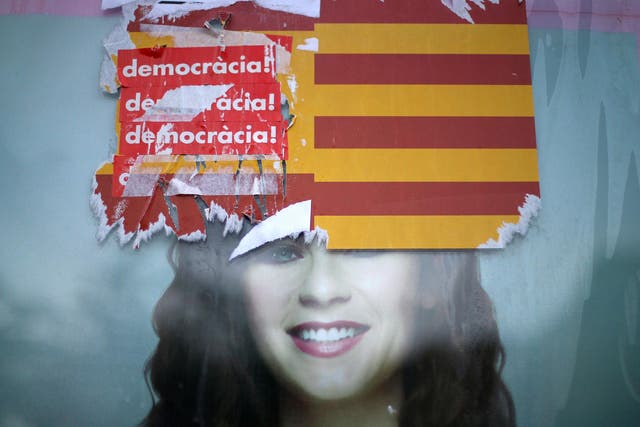 Stickers reading 'Democracy!' are seen on Spanish and Catalan flags during protests against the transfer of bank headquarters out of Barcelona
