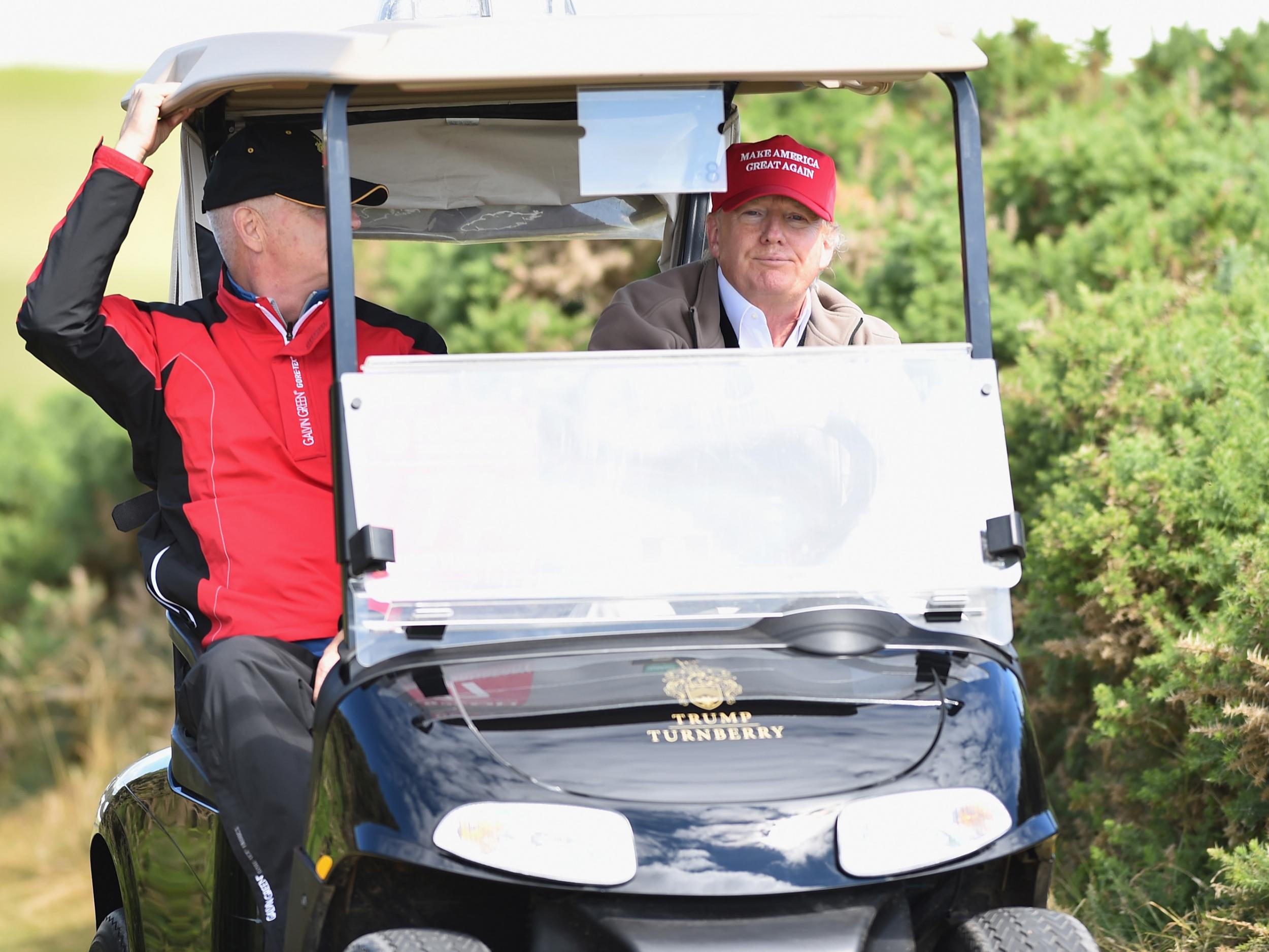 Donald Trump drives a golf buggy during his visits to his Scottish golf course Turnberry in 2016