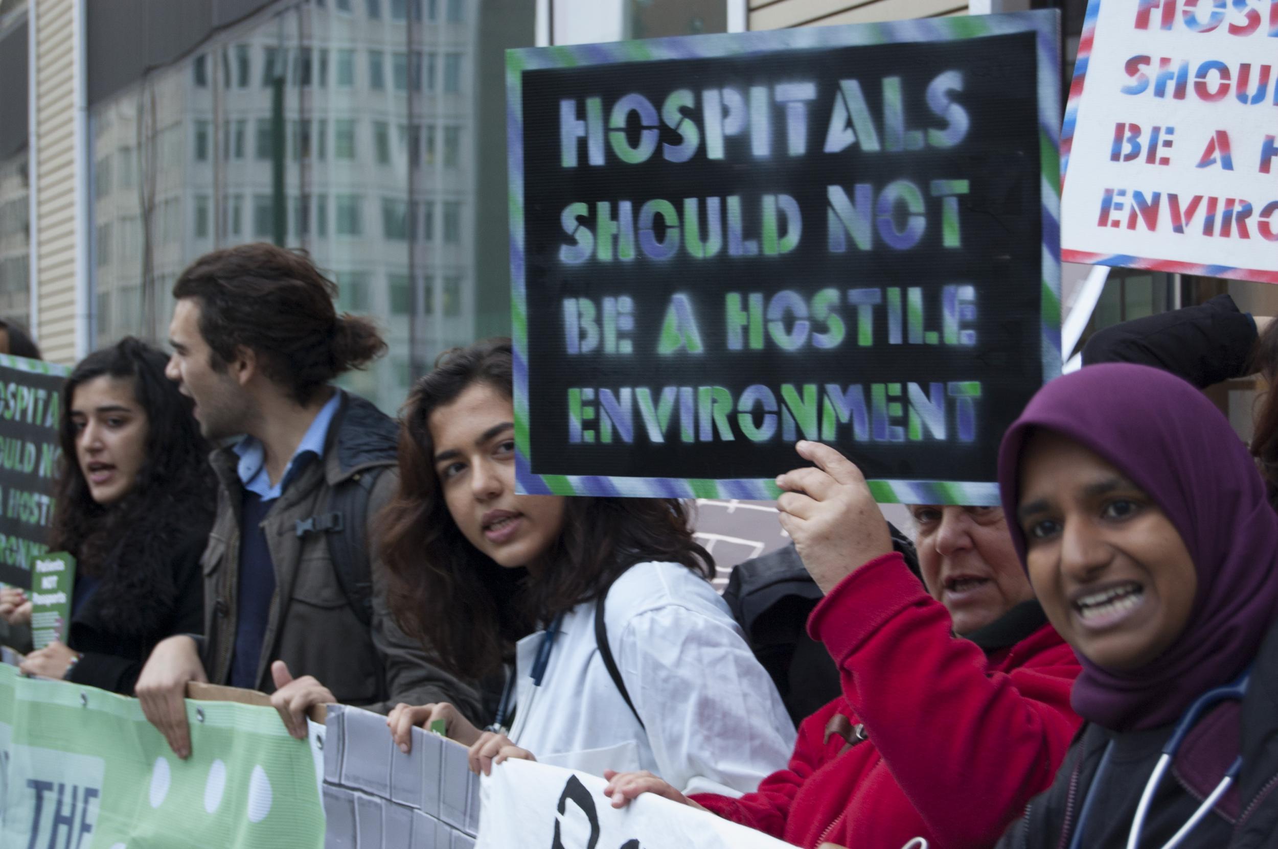 NHS staff and patients, with campaign group Docs Not Cops, are protesting outside the Department of Health against the introduction of immigration checks and upfront charging for NHS patients