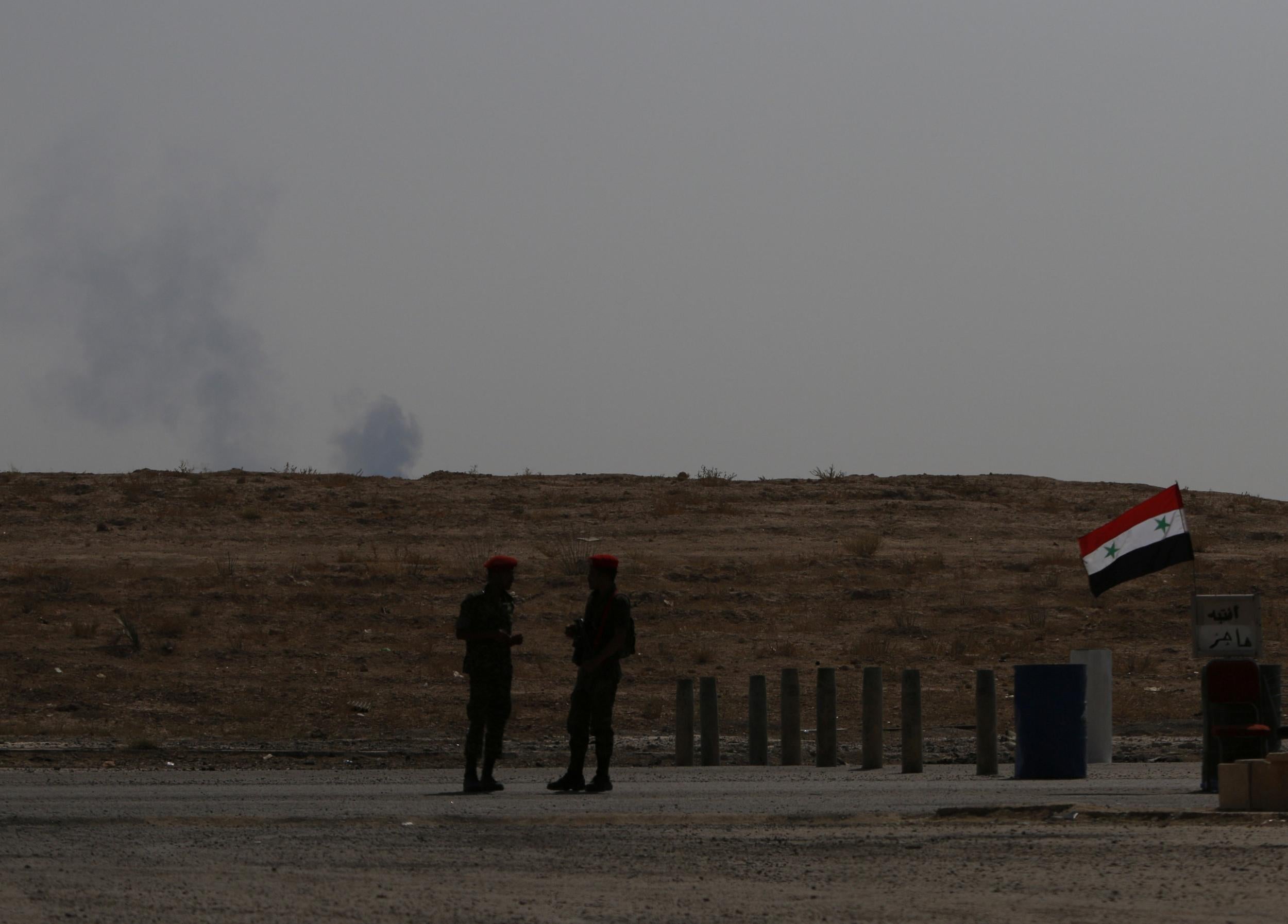 Smoke rises as Syrian army soldiers stand near a checkpoint in Deir Ezzor, Syria on 21 September 2017