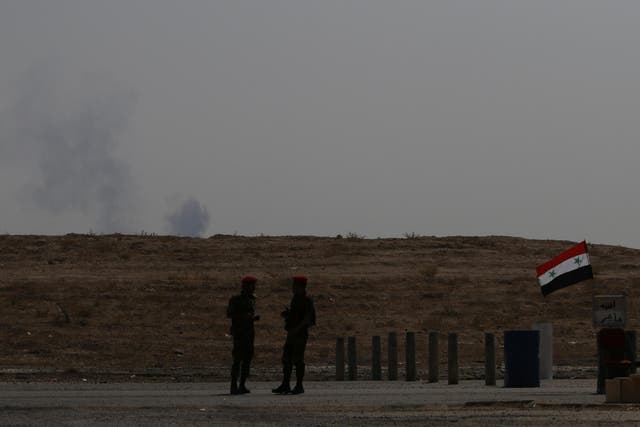 Smoke rises as Syrian army soldiers stand near a checkpoint in Deir Ezzor, Syria on 21 September 2017