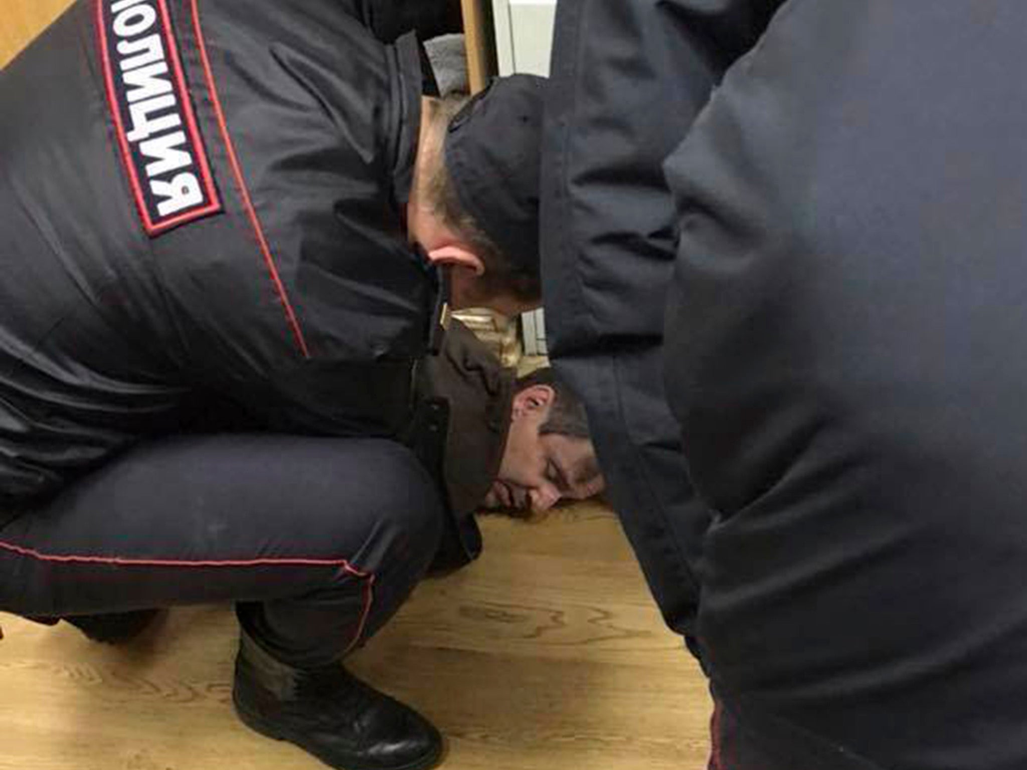 Police officers detain an unidentified man who reportedly stabbed journalist Tatyana Felgenhauer