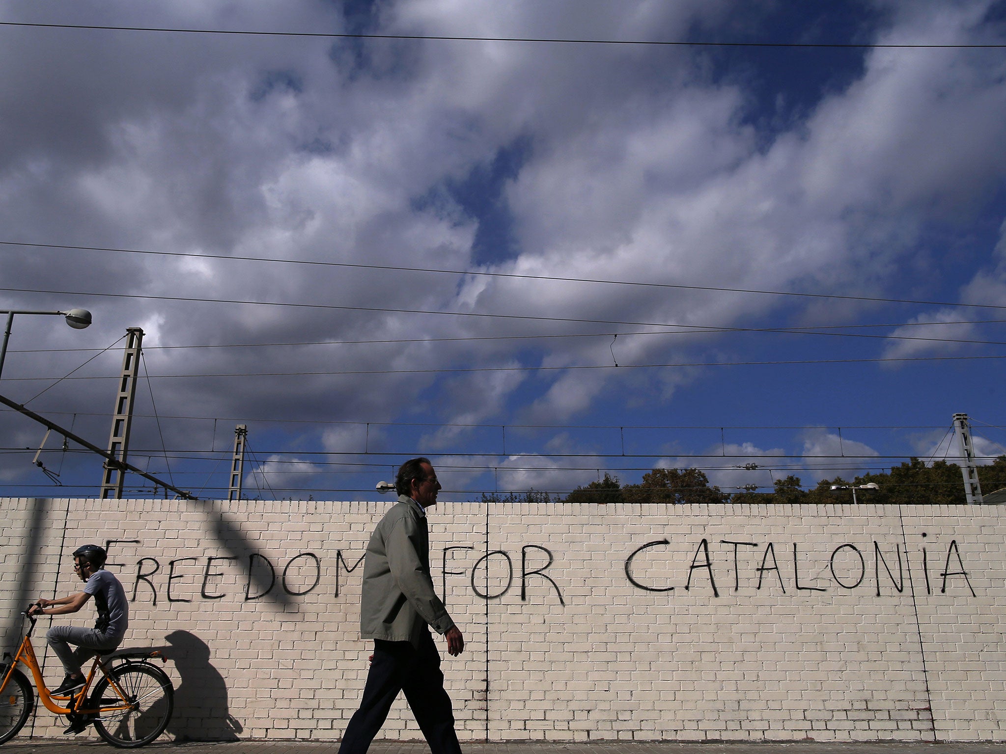 People pass in front of graffiti reading "Freedom for Catalonia" in Barcelona
