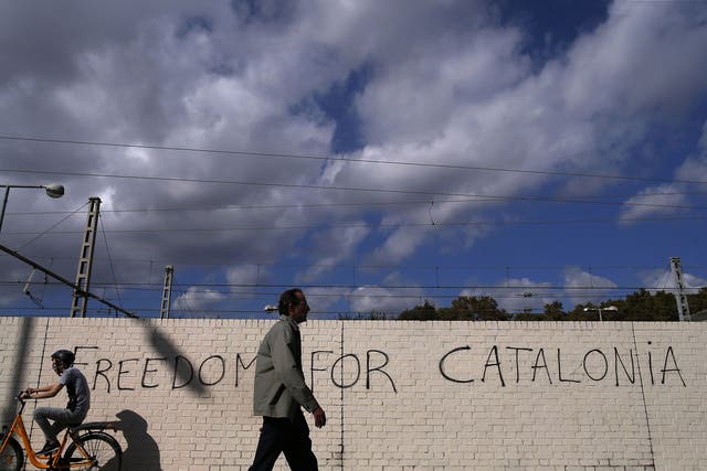 People pass in front of graffiti reading "Freedom for Catalonia" in Barcelona