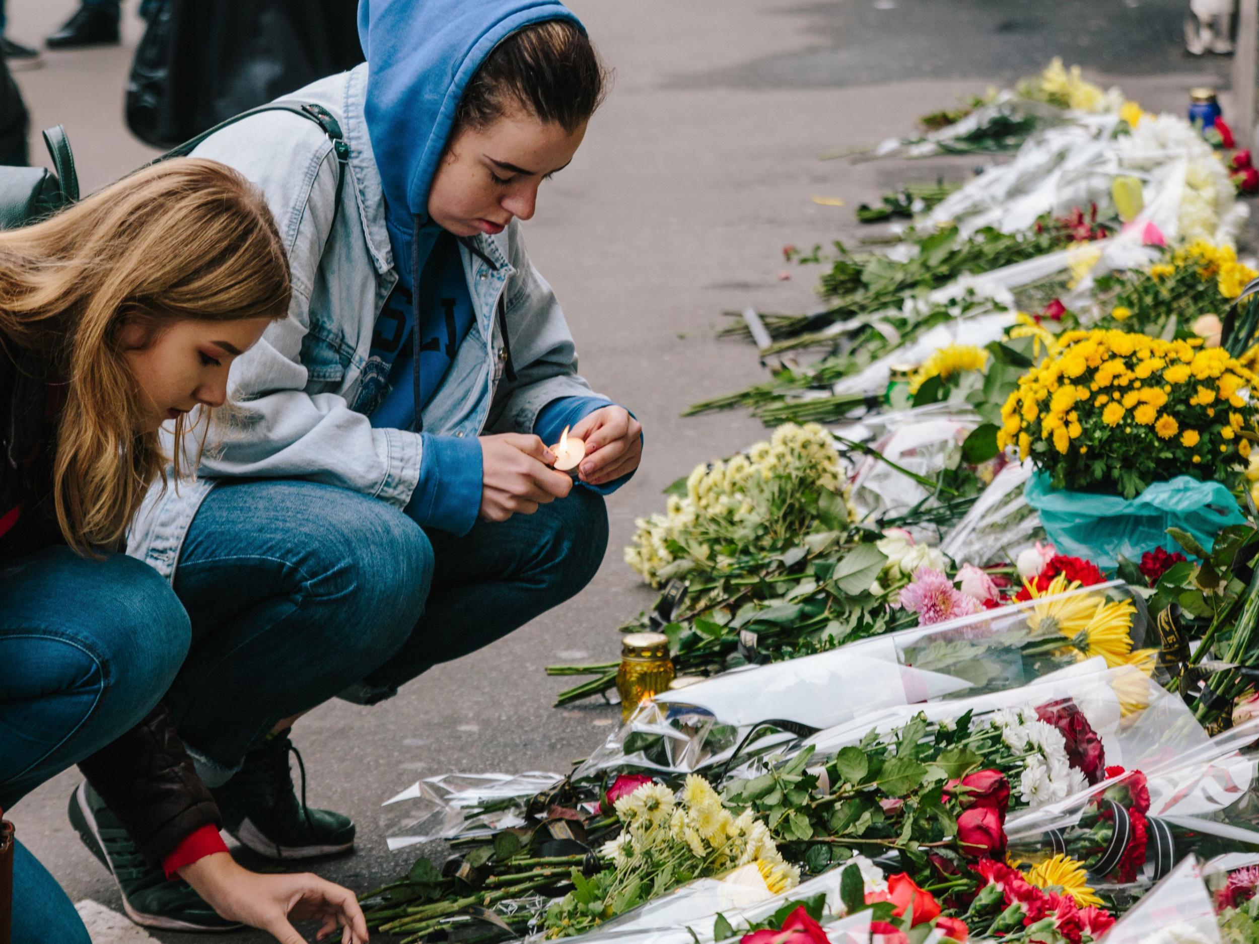 People lay flowers and light candles at the scene of the accident