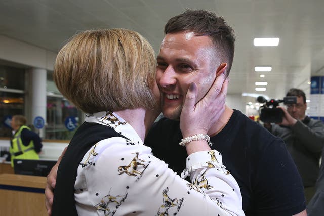 Jamie Harron, who was sentenced to three months in a Dubai jail for touching a man's hip, with his mother Patricia after arriving at Glasgow Airport
