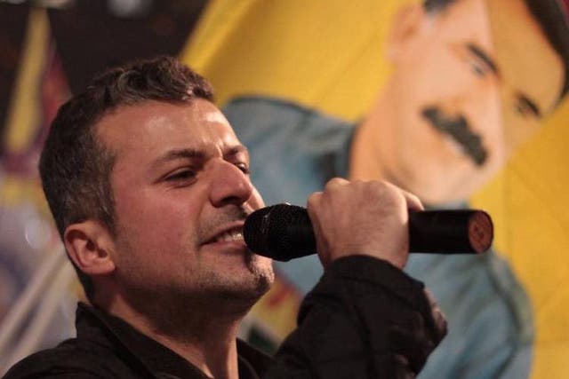 Mehmet speaking at a rally in London, with a poster of his hero Abdullah Ocalan, a Kurdish leader, in the distance