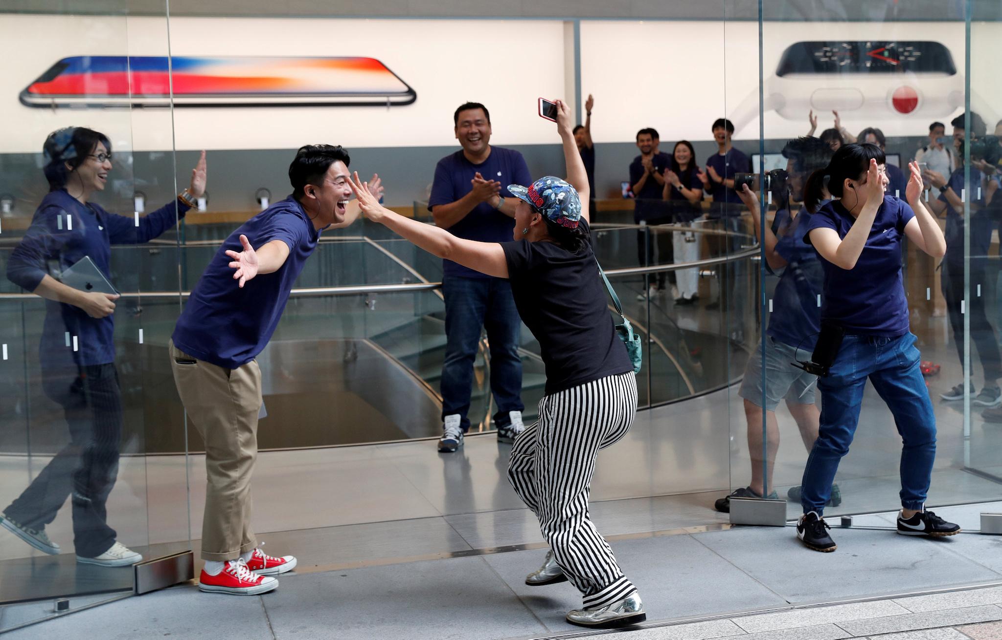 Apple fan Shoko Kimura (C), who has been waiting in line to purchase new Apple Watch, reacts with Apple Store staff as she enters the Apple Store in Tokyo's Omotesando shopping district, Japan, September 22, 2017