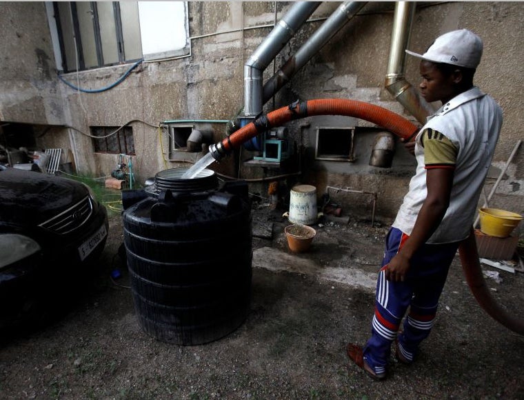 A man fills a tank with water in Tripoli, Libya