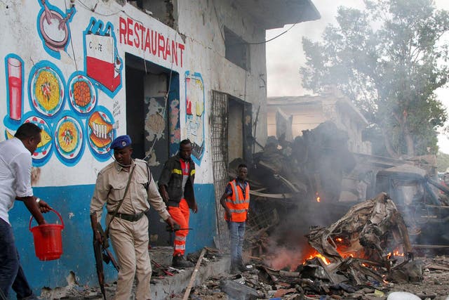 Somali security officers secure the scene of a suicide car bomb explosion, at the gate of Naso-Hablod Hotel in Hamarweyne district of Mogadishu, Somalia