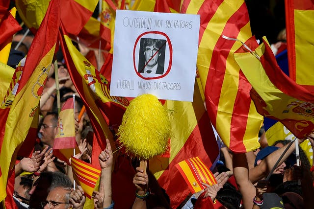 An anti-independence protester holding a portrait of Carles Puigdemont reading 'Dictators Out'. Thousands of protesters were out on the street to demand Catalonia remains part of Spain