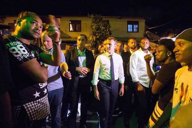 French President Emmanuel Macron speaks with residents during a visit to the Crique neighborhood in Cayenne as part of a three-day visit to French Guiana