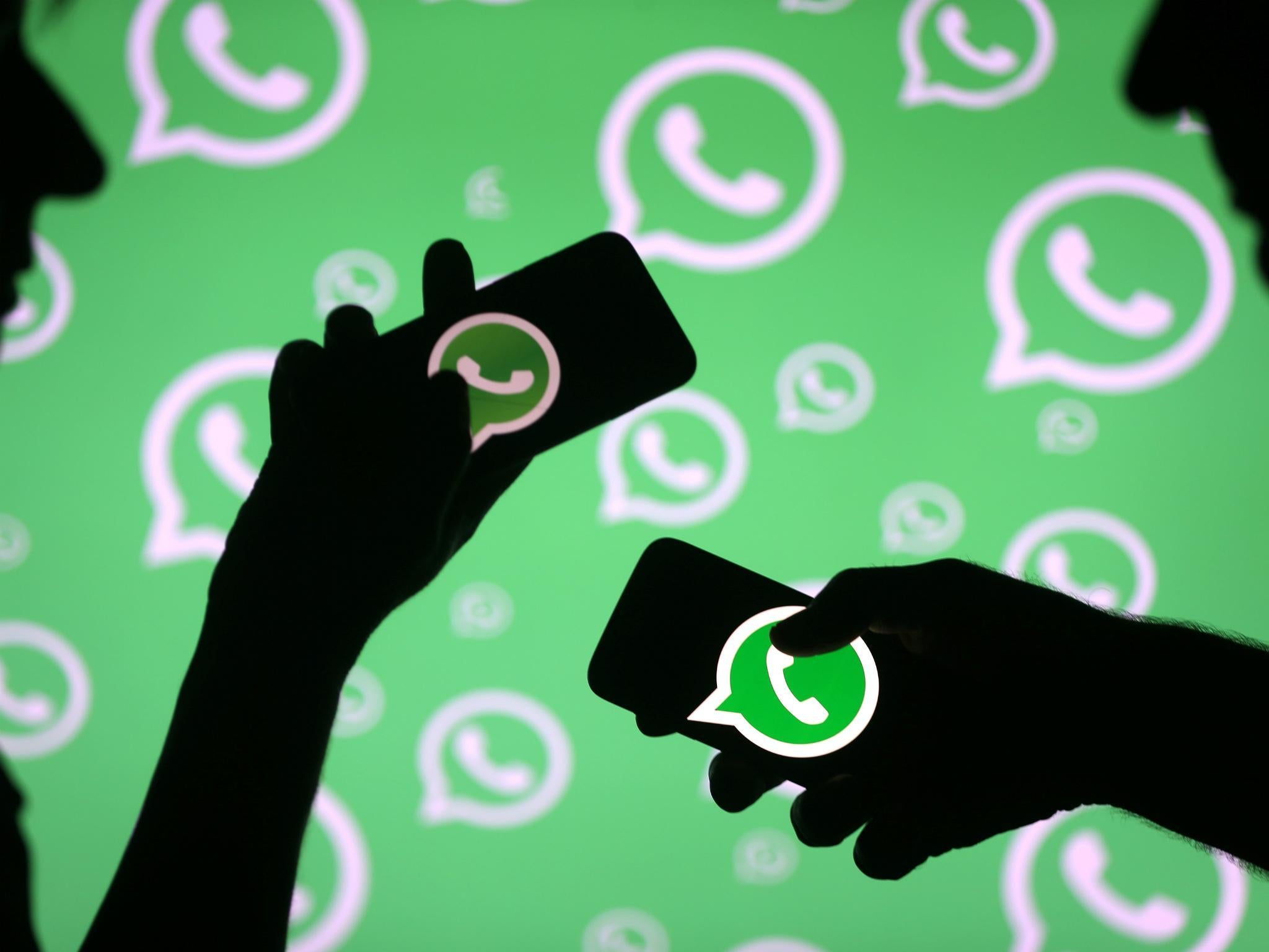 Men pose with smartphones in front of displayed Whatsapp logo in this illustration September 14, 2017