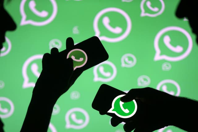 Men pose with smartphones in front of displayed Whatsapp logo in this illustration September 14, 2017