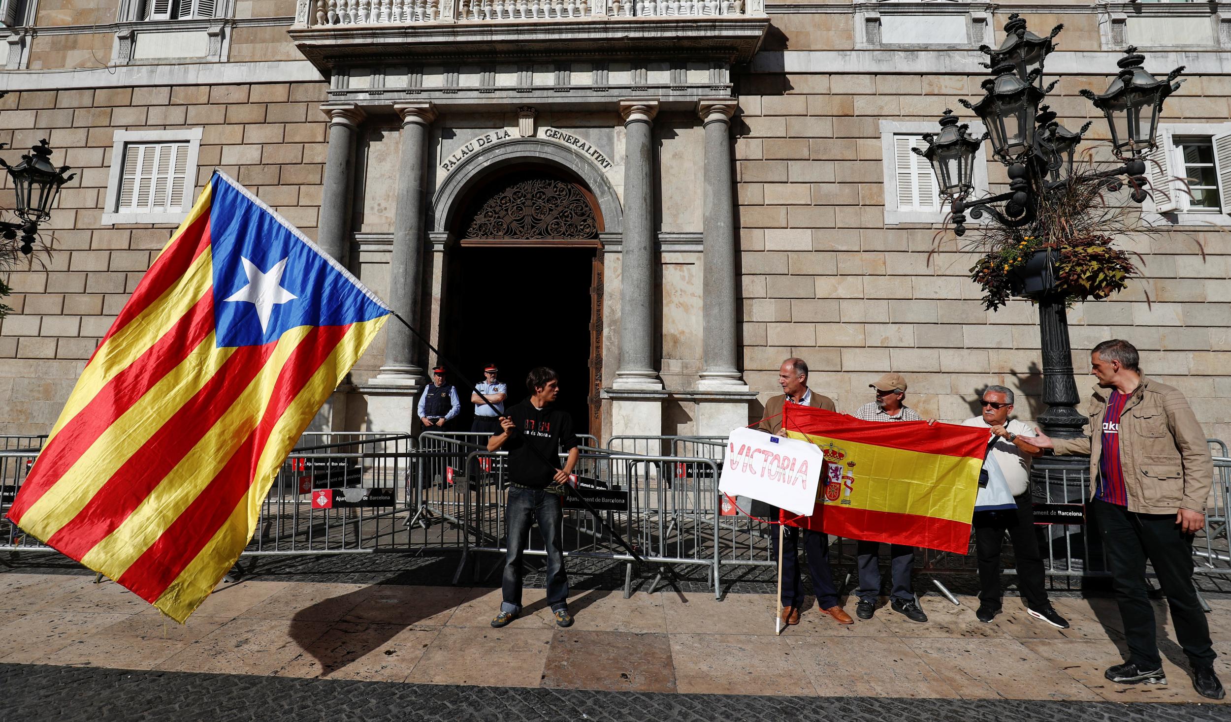A man holding a Catalan separatist flag looks at men holding a Spanish flag outside the Catalan regional government headquarters in Barcelona