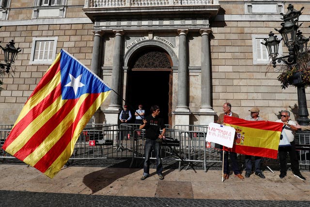 A man holding a Catalan separatist flag (L) looks at men holding a Spanish flag outside the Catalan regional government headquarters in Barcelona