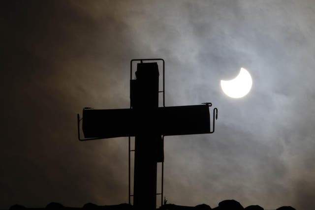 A picture taken on January 4, 2011 in Old Damascus shows the world's first partial solar eclipse of 2011 behind the cross of a church in a Christian neighbourhood of the Syrian capital