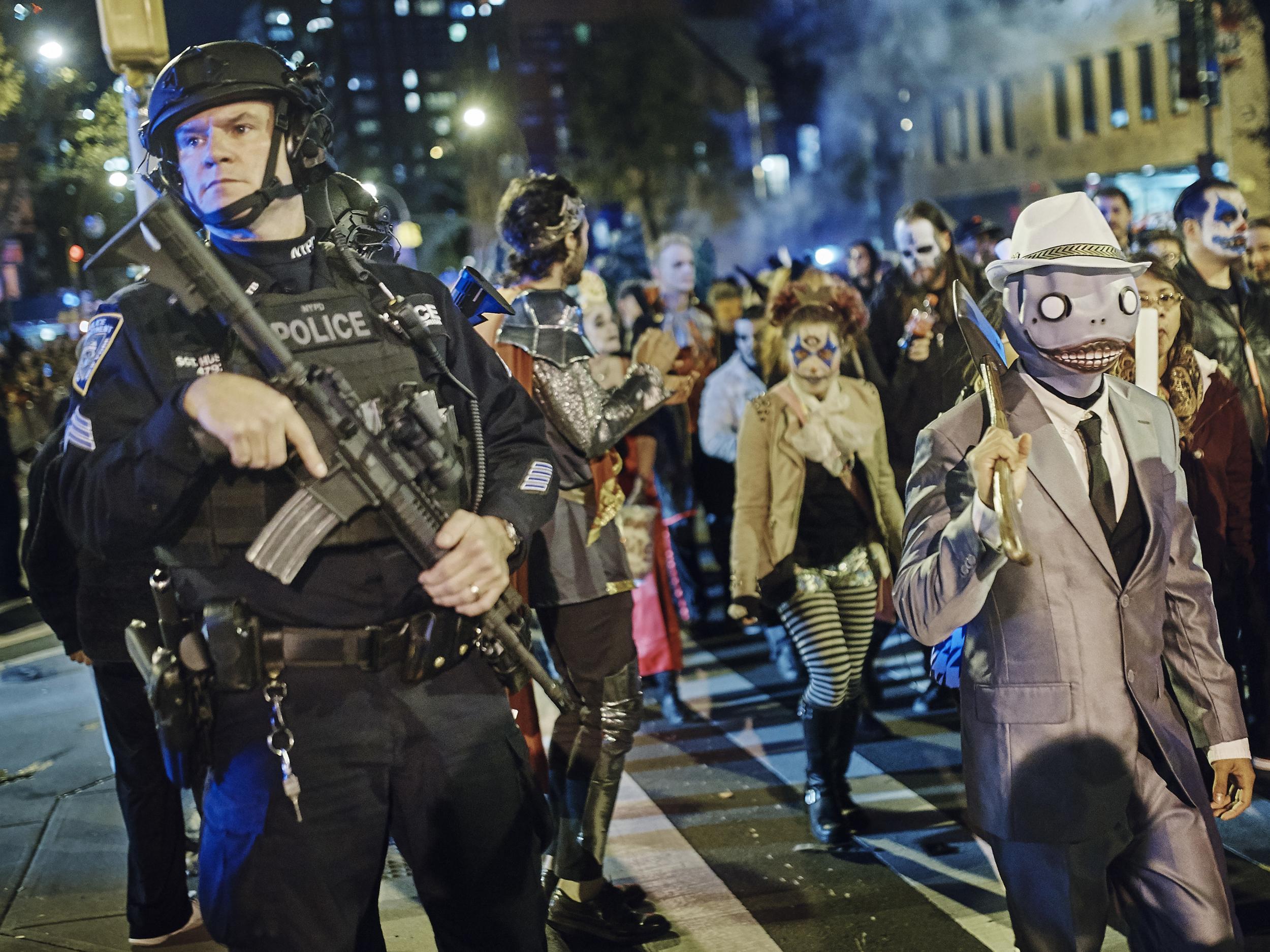 Heavily armed police stand guard as revellers march during the Greenwich Village Halloween Parade