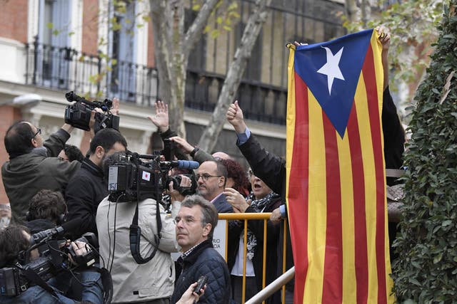 A protester holds a pro-independence Catalan Estelada flag next to journalists as members of the deposed Catalan regional government arrive at the National Court in Madrid