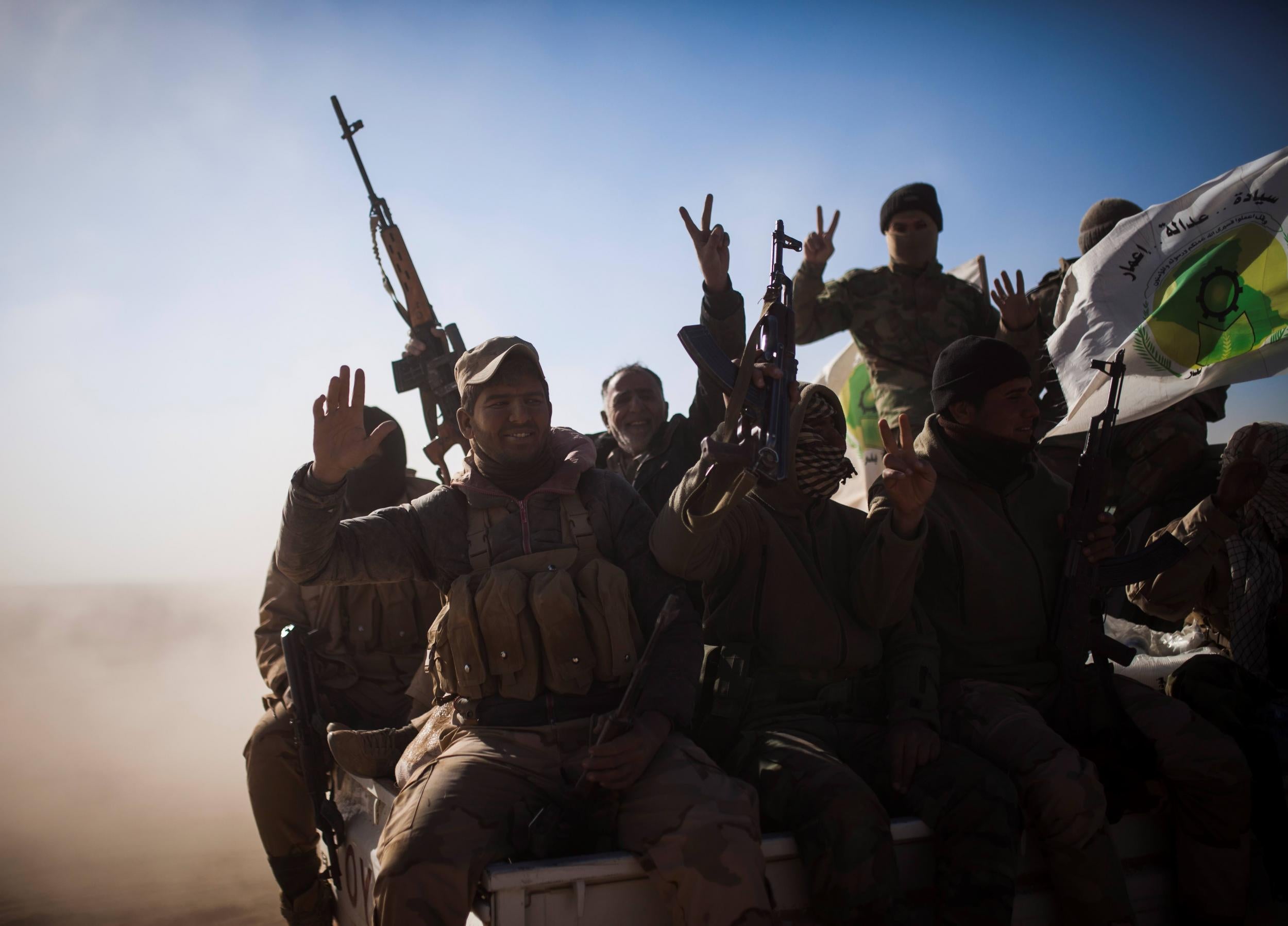 Soldiers of the Hashd al-Shaabi (Popular Mobilisation Units) wave the victory sign onboard a pickup truck