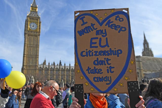 A demonstrator holds a placard reading "I want to keep my EU citizenship" as they pass the Houses of Parliament