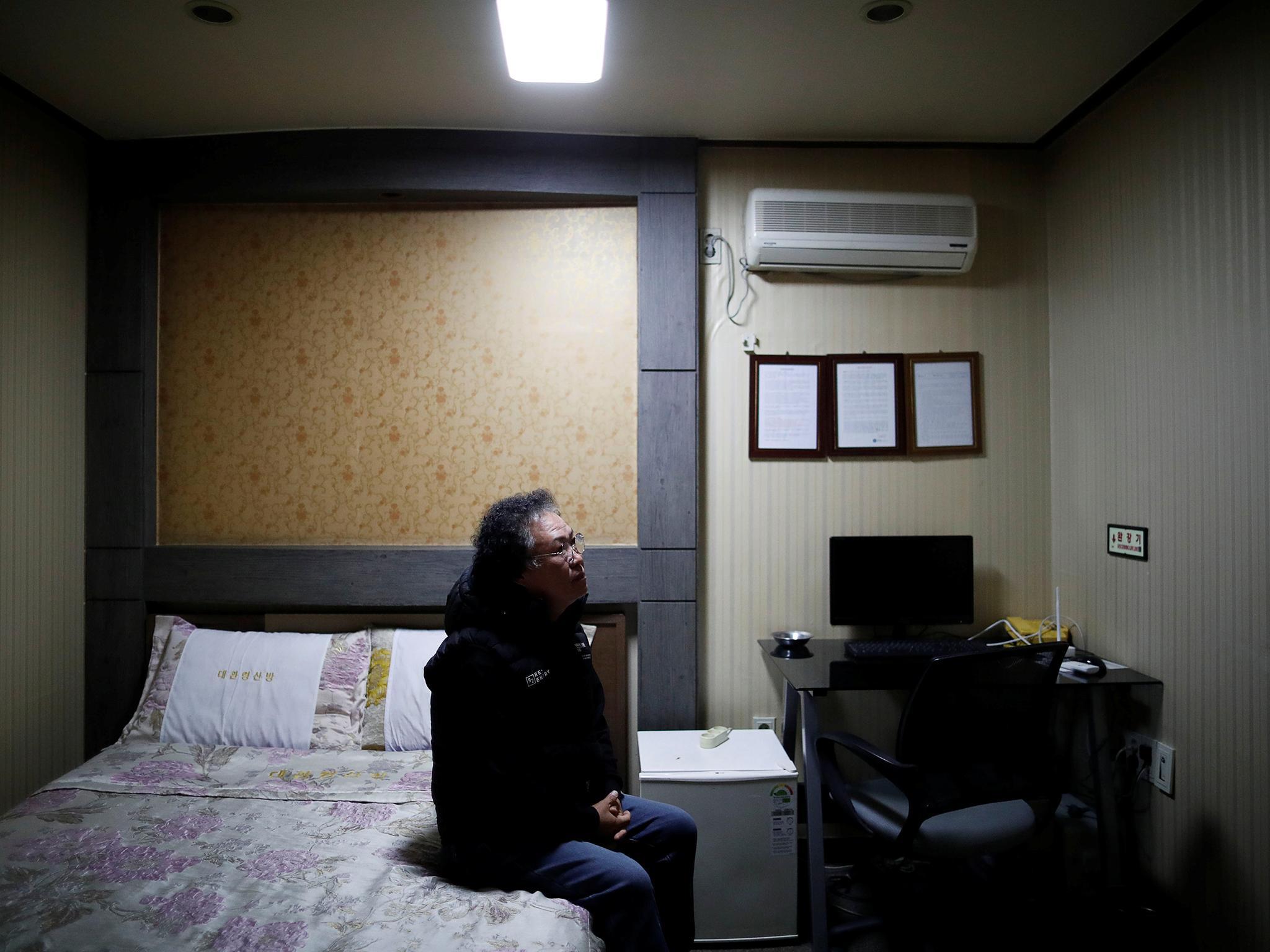 Oh Young-whyan, a 55-year-old motel owner, sits on a bed before an interview (Reuters)