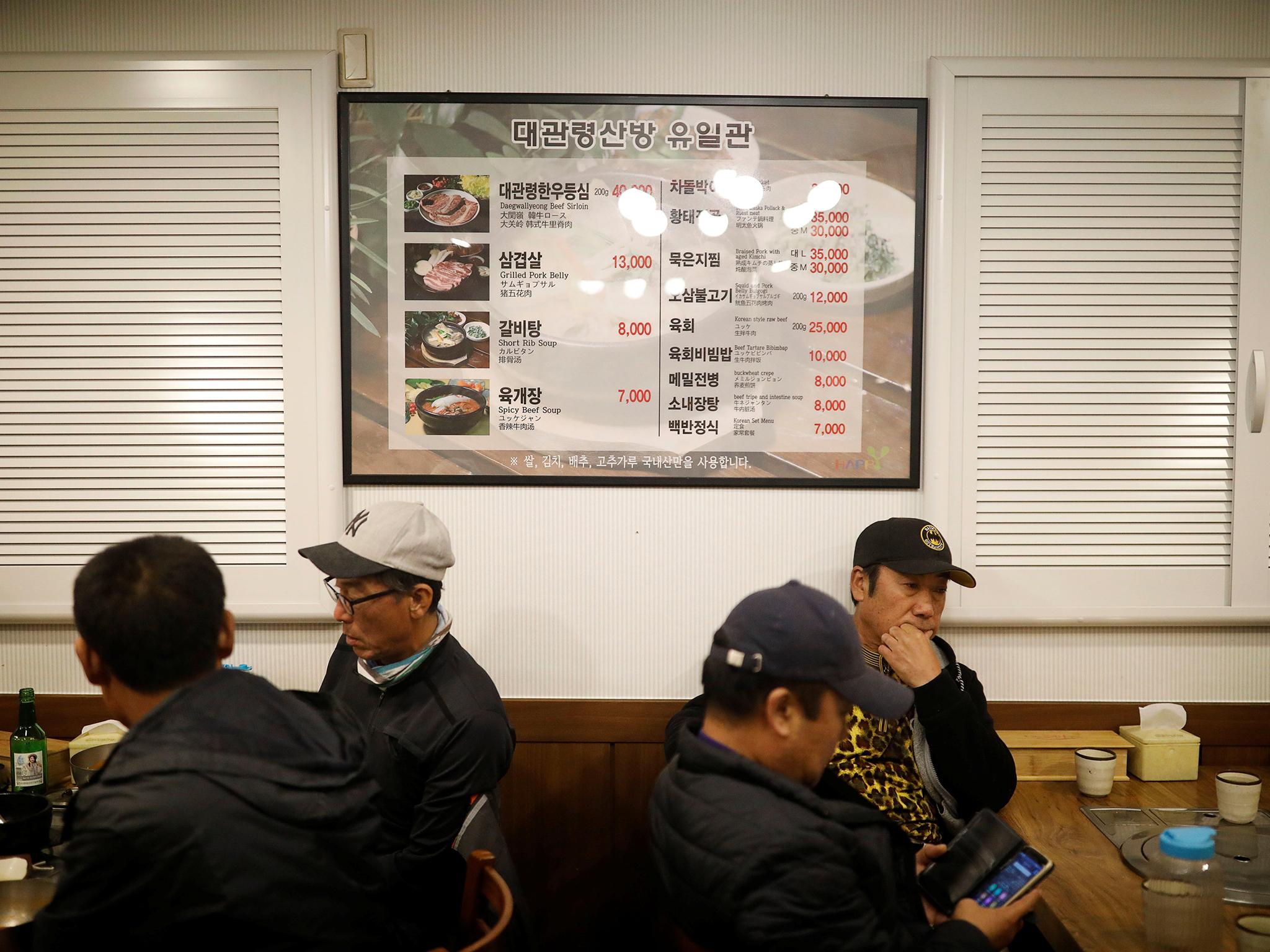 People eat in front of a menu translated into four different languages in a PyeongChang restaurant (Reuters)