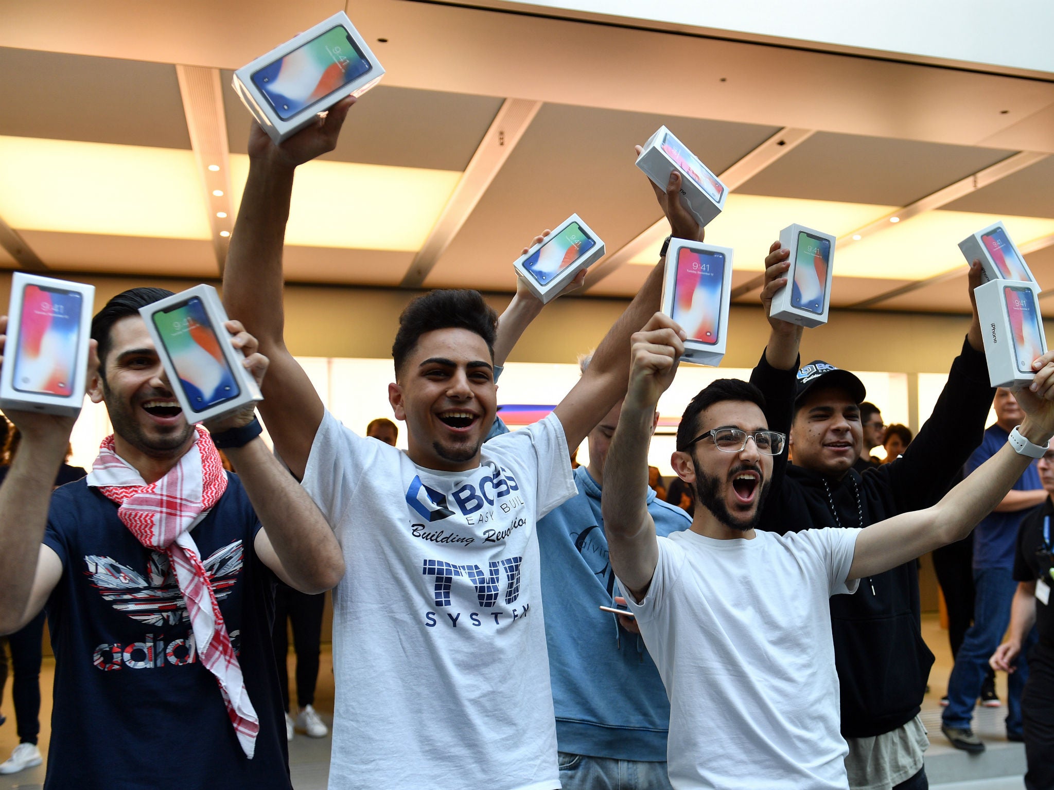 The first customers at an Apple showroom in Sydney display their iPhone X purchases